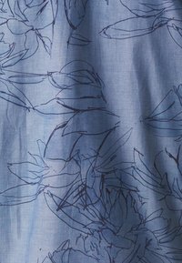 Tessuto azzurro chiaro con un motivo di contorno floreale blu scuro, con forme astratte di foglie e petali che creano un aspetto texture.