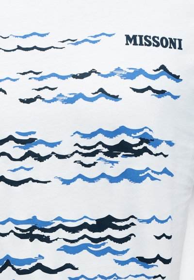 Λευκό βαμβακερό μπλουζάκι με μοτίβο κύματος σε διάφορες αποχρώσεις του μπλε και του μαύρου. Το λογότυπο "MISSONI" τυπωμένο μαύρο στο πάνω δεξί μέρος.