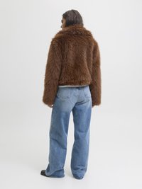 Brona mākslīgā kažokāda ar augstu apkakli, īsu dizainu un mīkstu tekstūru. Saskaņota ar gaiši ziliem platajiem džinsiem un melniem apaviem.