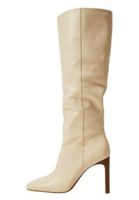 Botte haute beige en cuir avec un bout pointu et un talon stiletto effilé. Texture lisse avec des détails de couture minimaux.