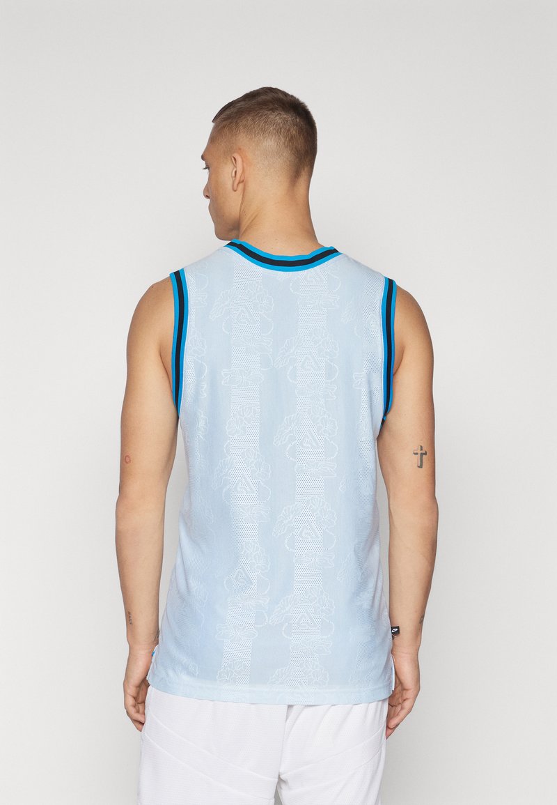 Un débardeur léger bleu clair avec un motif texturé, présentant une bordure bleu marine autour de l'encolure et des emmanchures. Vue de dos.