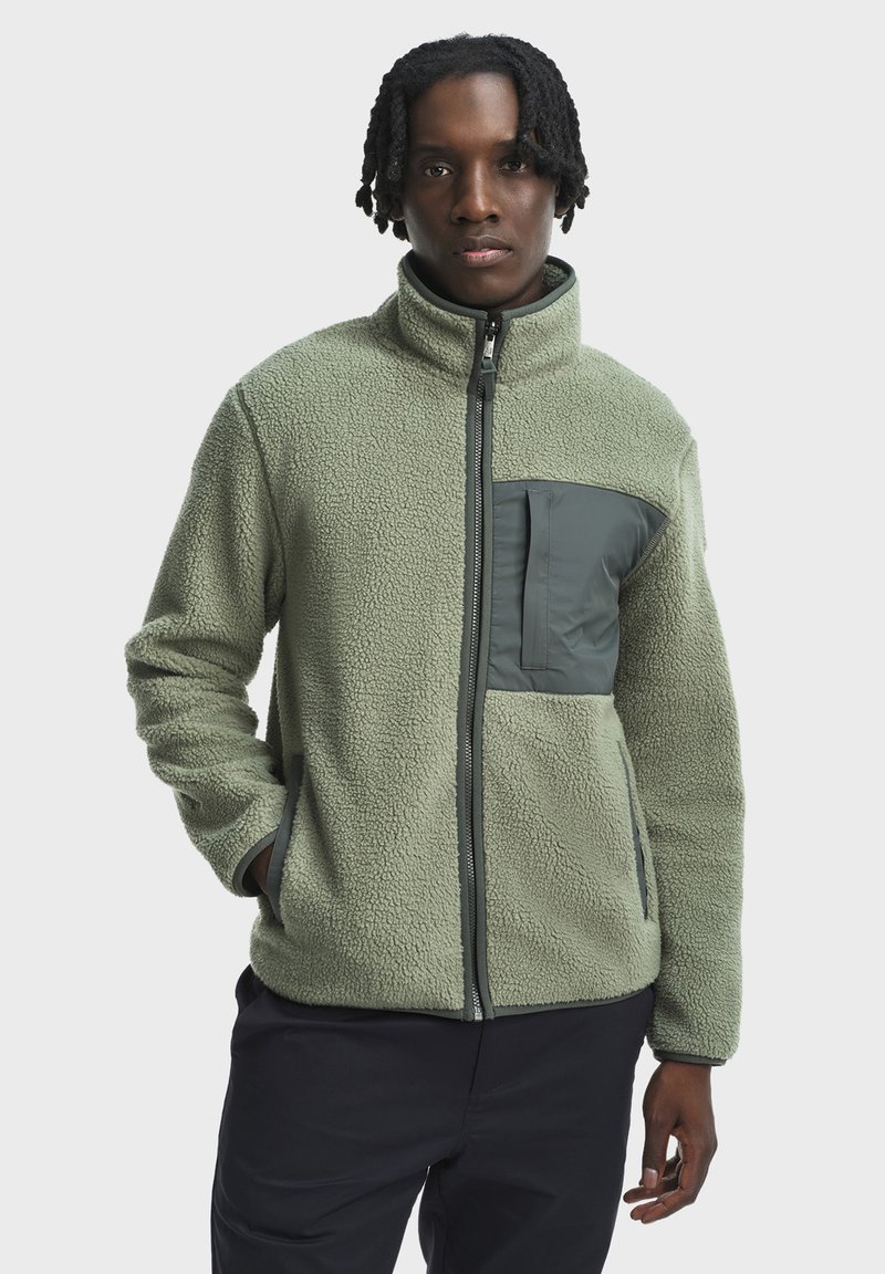 Fleece bunda v svetlozelenej farbe s textúrovaným povrchom, plným zipsom, stojacím golierom a tmavozelenou náprsním vreckom, obsahujúcim bočné vrecká.