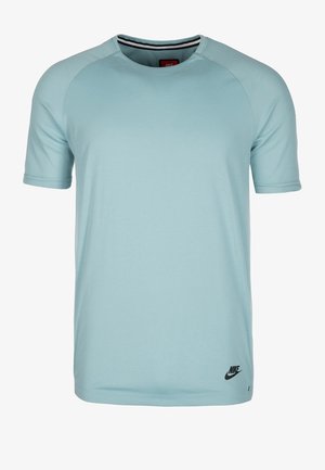 Jasnoniebieska sportowa koszulka Nike z krótkim rękawem, okrągłym kołnierzykiem i czarnym logo Nike w pobliżu dolnego brzegu po lewej stronie.