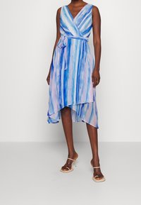 Vestido envolvente en rayas de acuarela azul y rosa, con escote en V y cintura con lazo. Dobladillo asimétrico fluido, hecho de un tejido ligero.