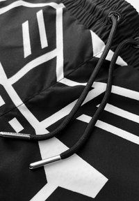 Zwarte stof met witte geometrische patronen, voorzien van zwarte trekkoorden en metalen aglets. Soepele textuur met een lichte glans.