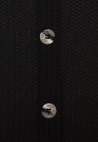 Zwarte gebreide cardigan met twee ronde knopen, één donker en één licht, die centraal aan de voorste sluiting zijn geplaatst.