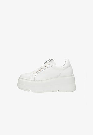 White platform sneakers with a textured rubber sole, featuring a smooth leather upper and gold-toned eyelets for laces.