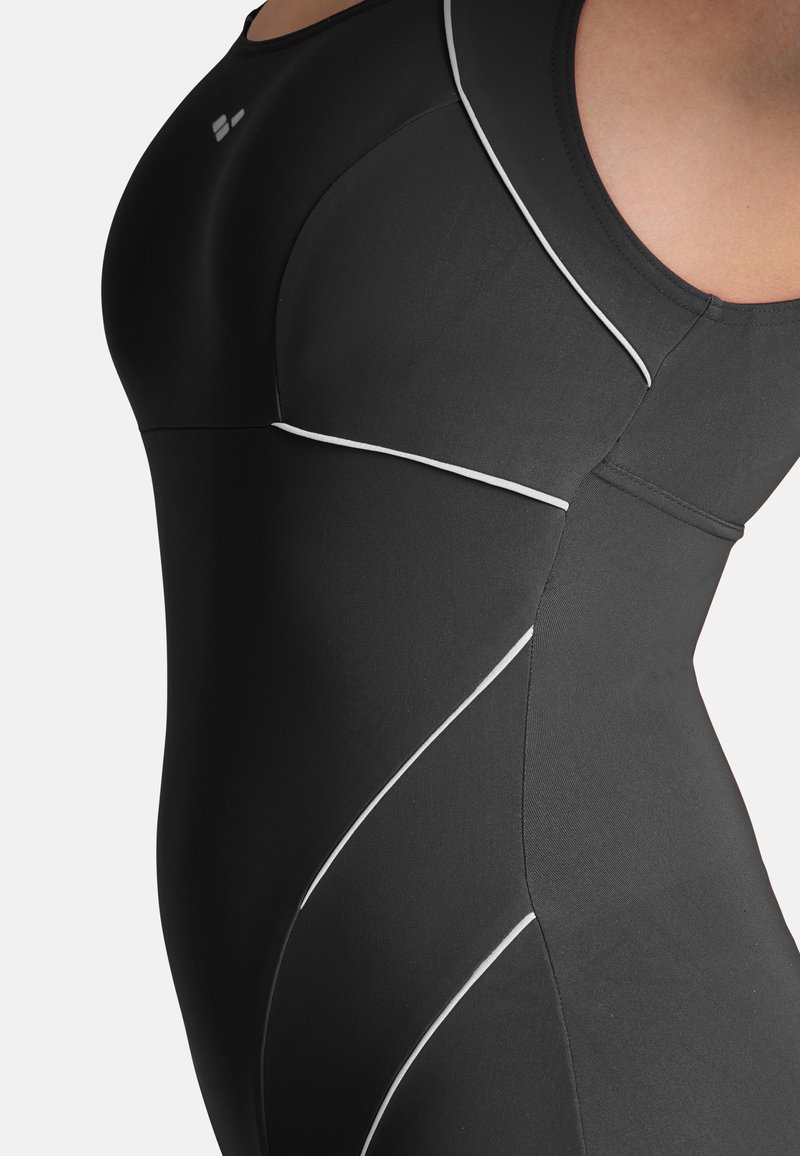 Maillot de bain noir avec un délicat passepoil blanc le long des coutures courbées, fabriqué dans un matériau lisse et extensible. Pas de quincaillerie ou de motifs visibles.