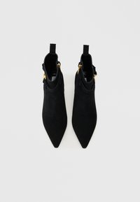 Black suede ankle boots with a pointed toe, featuring gold hardware accents and a pull tab on the heel for easy wear.