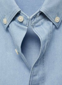 Colletto di camicia in denim azzurro chiaro con chiusure a bottone, caratterizzata da una texture liscia e cuciture ordinate. Aperta al colletto per una vestibilità informale.