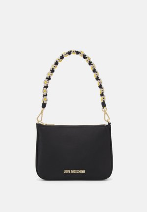 Sac à main synthétique noir avec une poignée tressée ornée de marguerites noires, blanches et jaunes. Ferrures dorées et fermeture à glissière. Marque visible.