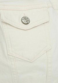 Tela de mezclilla blanca que muestra un bolsillo en el pecho con costuras contrastantes en color rosa y un botón automático de metal con la inscripción "ONLY".