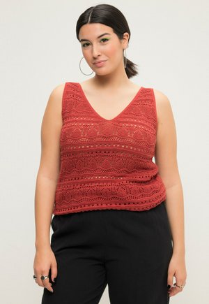 Rød strikket tanktop med V-hals, prydet med hulmønstre og en tekstureret design. Parret med sorte bukser i afslappet pasform.