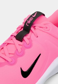 Rosa Nike-sneaker med en teksturert overdel, svart detaljer på tungen og snøringer. Har en iøynefallende svart swoosh-logo på siden.