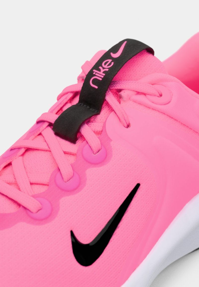Sneaker Nike rosa con tomaia testurizzata, dettagli neri sulla linguetta e sui lacci. Presenta un audace logo swoosh nero sul lato.
