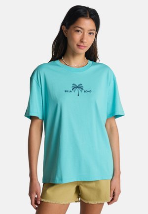 Lichtblauw katoenen T-shirt met korte mouwen, voorzien van een palmbomenafbeelding en de tekst "BILLA BONG" in het zwart. Losse pasvorm, ronde halslijn.
