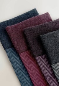 Cztery swatchy materiałów z teksturowanej dzianiny w różnych kolorach: ciemnoniebieskim, burgundowym, ciemnofioletowym i ciemnoszarym, z wzorem w jodełkę.