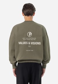 Olive green sweatshirt with a relaxed fit, crew neckline, and ribbed cuffs. Features white printed text and logo on the back.