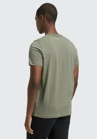 Zielona oliwkowa bawełniana koszulka z krótkimi rękawami, prostym krojem i małym logo na plecach. Gładka faktura, minimalistyczny design.