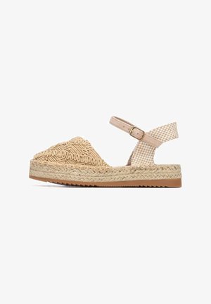 Sandalia alpargata beige con parte superior tejida, diseño triangular, detalles texturizados, correa ajustable en el tobillo y suela de yute trenzado.