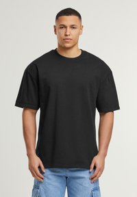 Sort, oversized t-shirt lavet af bomuld. Rund hals, korte ærmer og en afslappet pasform. Ingen synlige mønstre eller hardware.