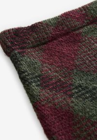 Gros plan sur un tissu en laine douce avec un motif à carreaux vert foncé et bordeaux et une texture duveteuse.