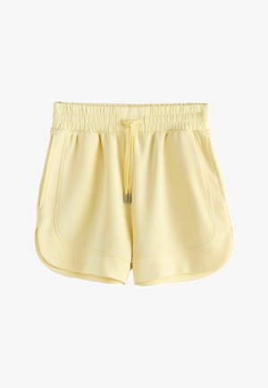 Világos sárga, hétköznapi rövidnadrág elasztikus derékpánttal, húzózsinórral, oldalsó zsebekkel és lekerekített szegéllyel, fehér háttéren bemutatva.