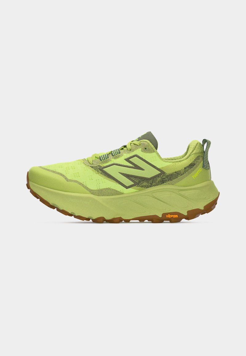 Zapatilla de trail running verde claro con suela gruesa, suela exterior Vibram marrón, logotipo "N" de New Balance y texto "hierro" en la parte superior de malla.
