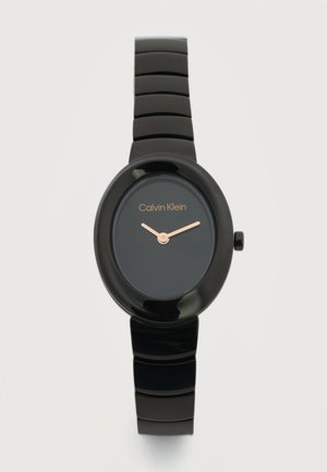 Czarny zegarek na rękę Calvin Klein z owalną tarczą, minimalistycznym wzornictwem, złotymi wskazówkami godzinową i minutową oraz błyszczącym, segmentowym paskiem na jasnym tle.