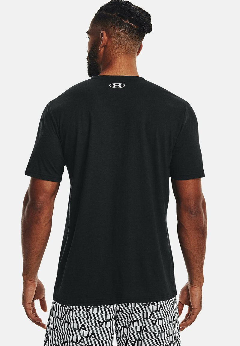 T-shirt noir à manches courtes en coton, avec un col rond et un logo blanc au dos. Texture lisse avec une coupe décontractée.