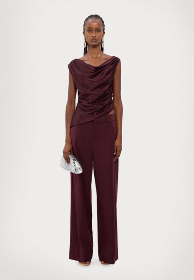 Bordeaux draperad satintopp med vida matchande byxor, som har en strömlinjeformad silhuett och en metallisk clutch med texturerad design.