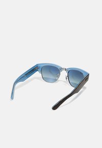 Ochelari de soare cu tentă albastră, având un cadru geometric, cu accente clare și brațe în nuanță de brun, evidențiind un design modern.
