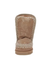 Bota de ante color marrón claro con puntera redonda, costuras blancas en contraste y acabado texturizado; cuenta con un forro suave y suela plana.