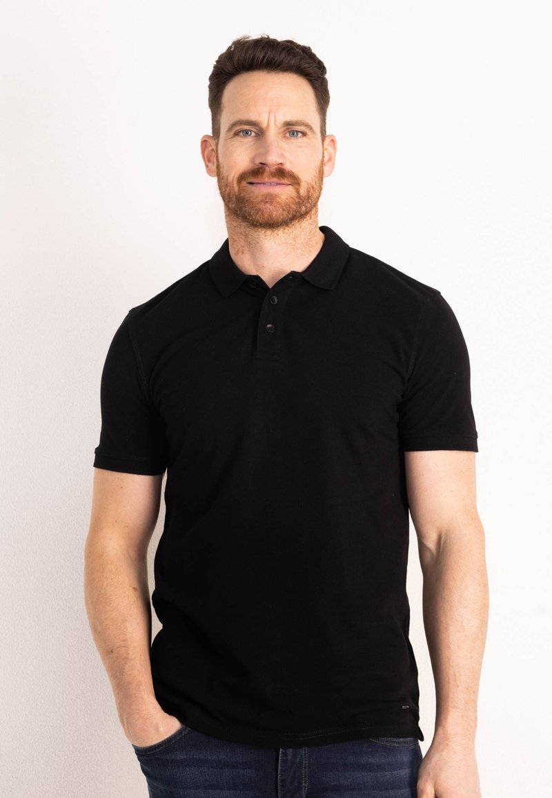 Černá polo košile z bavlny, s límečkem, třemi knoflíky a krátkými rukávy. V kombinaci s modrými džíny.
