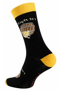 Schwarze Socken mit gelbem Bündchen und Zehen, die ein Fass- und Textdesign in Braun, Creme und Gelb aufweisen. Material aus Baumwollmischung.