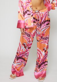 Set di pigiama in raso con un vivace motivo tropicale in arancione, rosa e teal, composto da pantaloni a gamba larga e polsini in raso a contrasto.