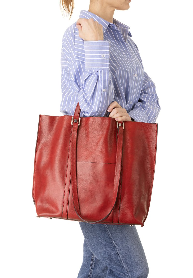 Borsa tote in pelle rossa con texture liscia, due manici lunghi e una tasca frontale. La borsa ha una forma rettangolare e una costruzione robusta.