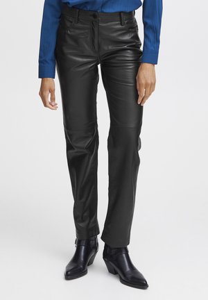 Black leather pants with a straight design, featuring front pockets and seams. Worn with black heeled boots.