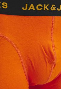 Boxers ajustados de algodón naranja para hombre con una cinturilla negra que presenta la marca "JACK & JONES" en amarillo, mostrando una textura suave y costuras cosidas.
