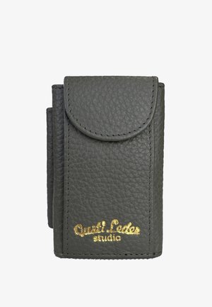 Grijze, gestructureerde leren portemonnee met afgeronde klep en goudkleurig, gedrukt "Gusti Leder studio" logo aan de voorkant, rechtop staande op een witte achtergrond.