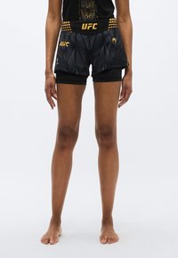 Črne atletske kratke hlače z vzorčnim dizajnom, z zlatim UFC logotipom na pasu in straneh. Narejene iz lahke, raztegljive tkanine.