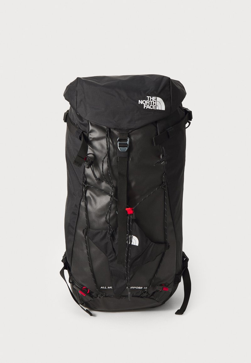 La mochila negra cuenta con una solapa superior, correas ajustables, cuerdas elásticas y un logotipo de la marca. Está hecha de un tejido duradero con un diseño elegante.