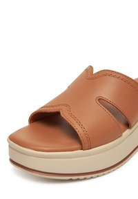 Barna bőr, nyitott orrú, csúszó szandál, hullámos varrásmintával és bézs platformtalppal.