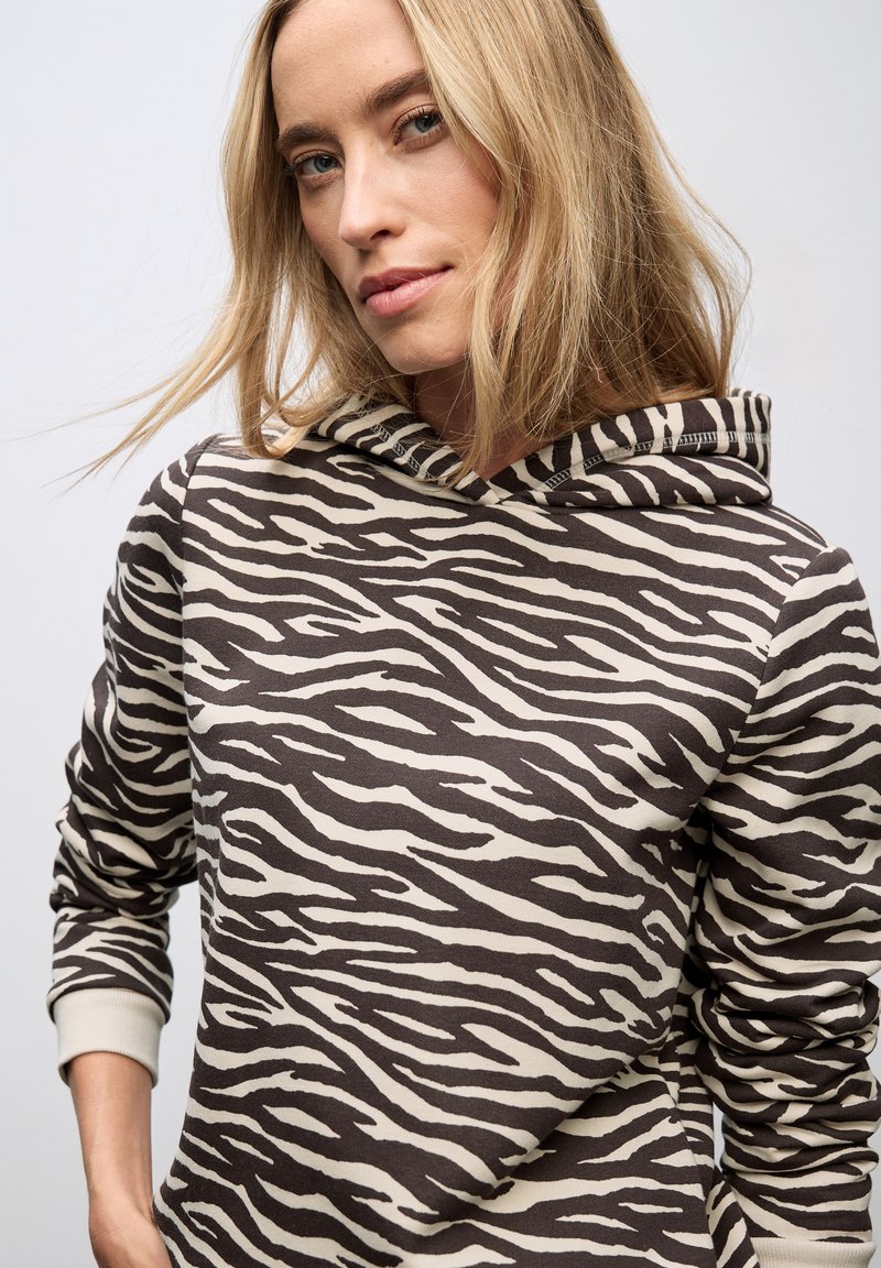 Sudadera a rayas de cebra en marrón y crema, con capucha ajustable y puños acanalados. Fabricada en un tejido suave y texturizado.