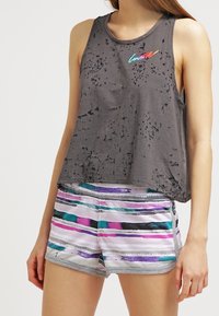 Top gris sin mangas con textura desgastada y logo "Converse" multicolor, combinado con shorts de rayas multicolores que presentan una cinturilla gris.