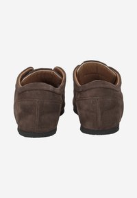 Mocassins en suède marron avec un profil bas, un dos arrondi et une semelle en caoutchouc noire. Intérieur doublé de cuir clair, avec des accents de couture.