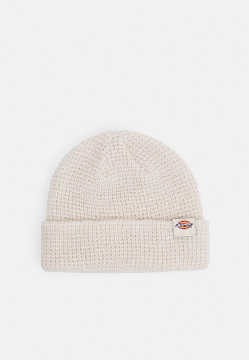 Stickad mössa i ljusbeige med en texturerad design och en vikbar kant. Har en liten, rektangulär varumärkets etikett på sidan.