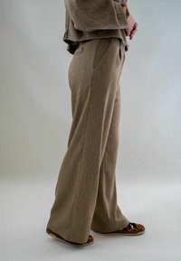 Lichtbruine, gestructureerde wijde broek met zijzakken. Gepaard met zwarte en luipaardprint instappers.