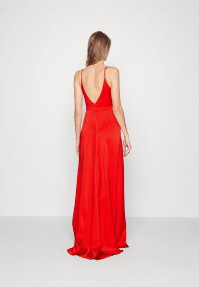 Abito da sera in raso rosso con scollatura a V profonda e spalline sottili, caratterizzato da una gonna fluida che si adagia sul pavimento.