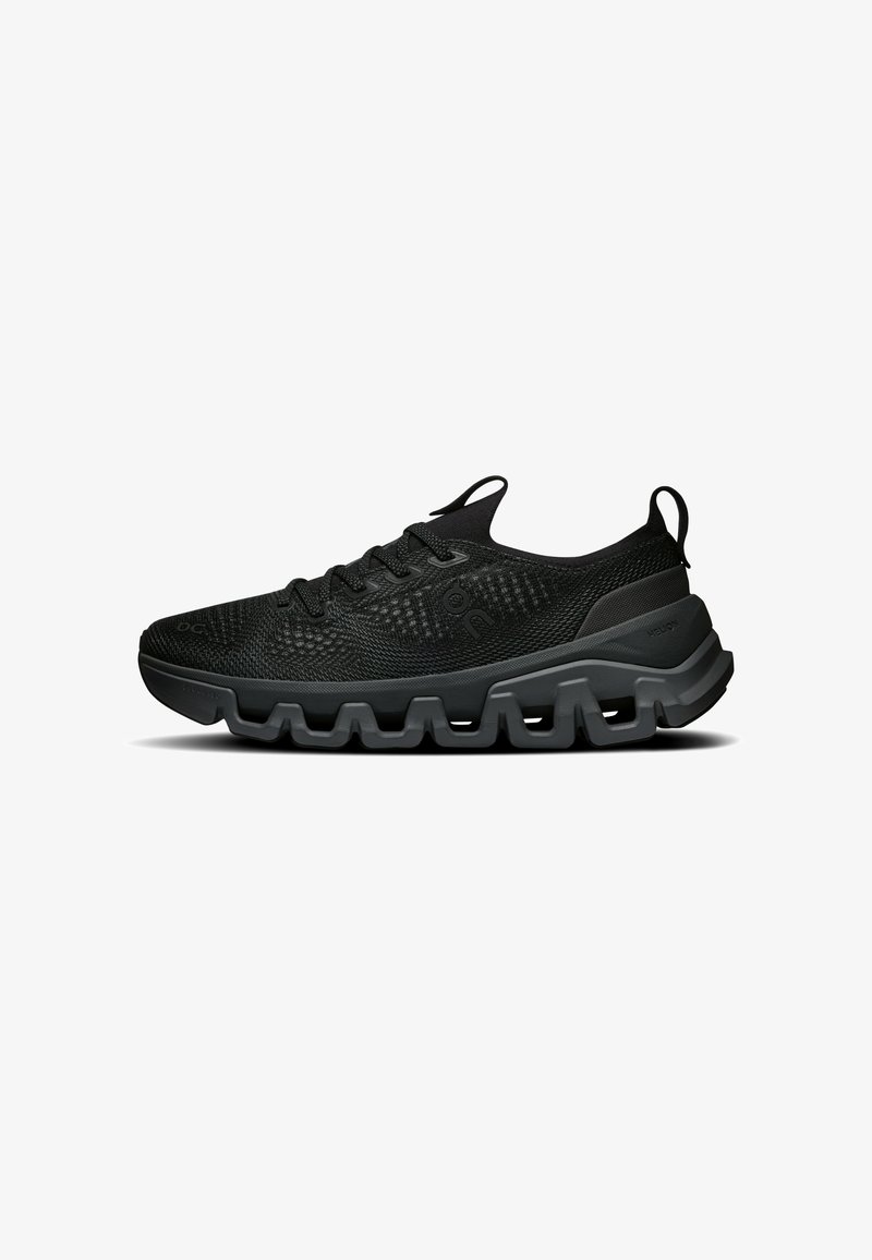 Basket athlétique noire avec dessus en mesh, fermeture à lacets et semelle épaisse segmentée conçue pour l'amorti et le soutien.